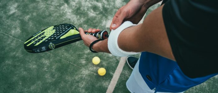 Photo by Oliver Sjöström Close-up of a male padel player adjusting wristband on a court. Sports action focused.